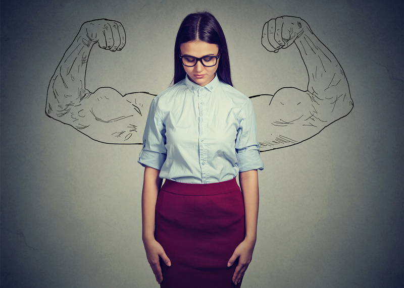Woman looking upset and doubtful of self with strong arms drawn behind her in background. Concept of imposter syndrome.