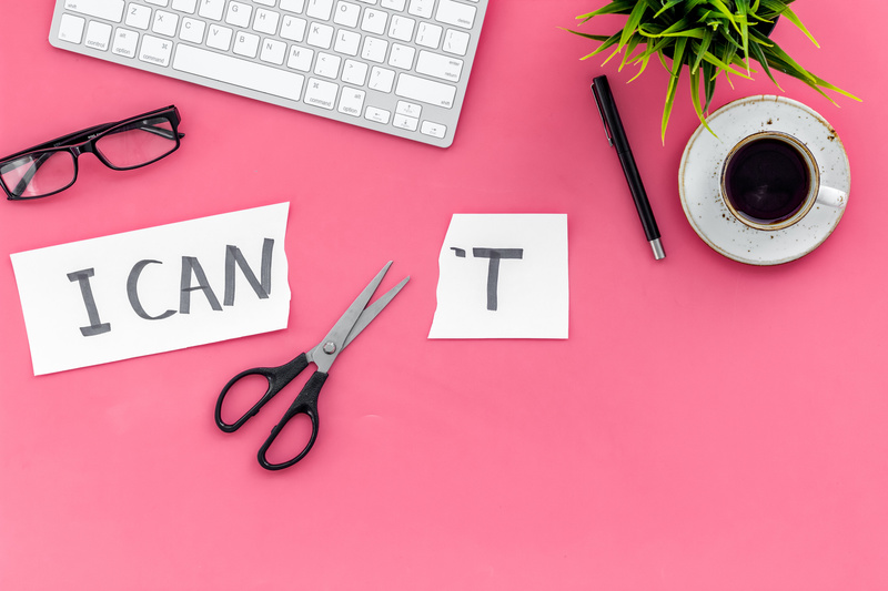Paper with 'I can't' cut in half with scissors on a pink background with a pair of glasses and keyboard. Success at work concept. data-cke-saved-src=