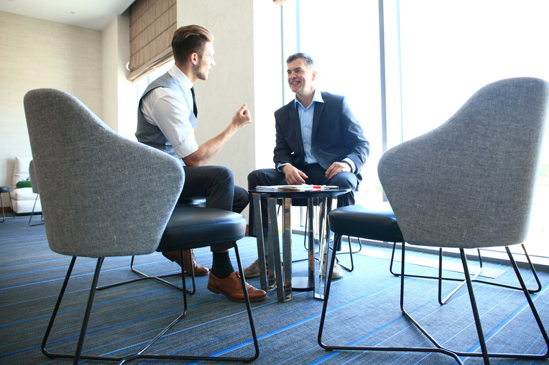Businessmen in modern, light office chatting and laughing.
