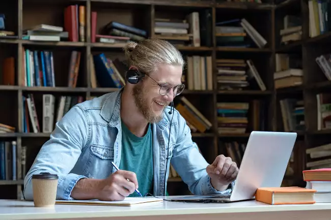 Man in library having an online tutorial with tutor.