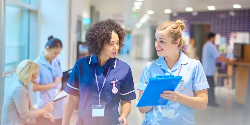 Two Nurses Talking In Hospital Corridor