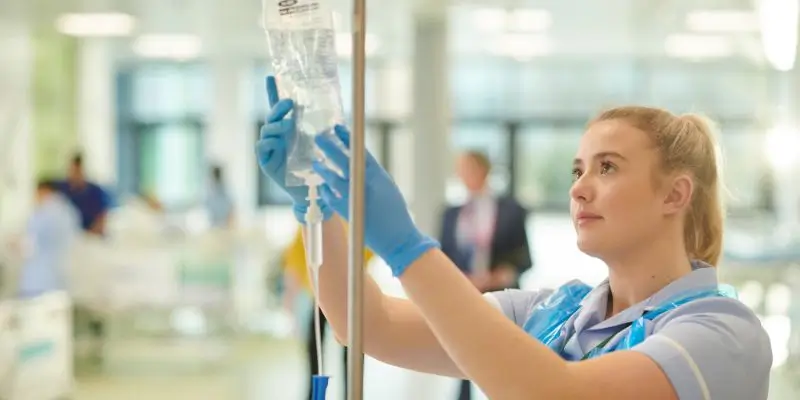 NHS Nurse Putting Up A Fluid Bag For Patient