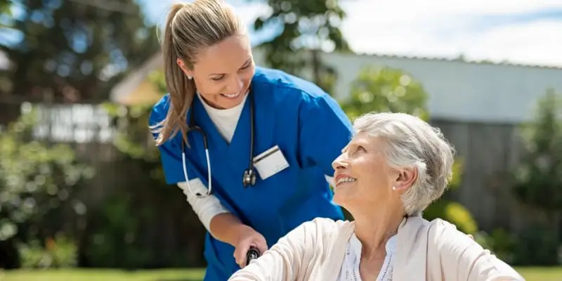 Private Nurse Talking To Elderly Patient In A Wheelchair