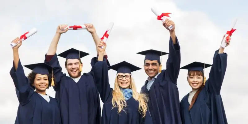 Graduates Celebrating In Robes Holding Scrolls