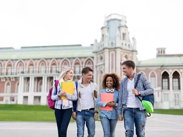 four students standing in front of university