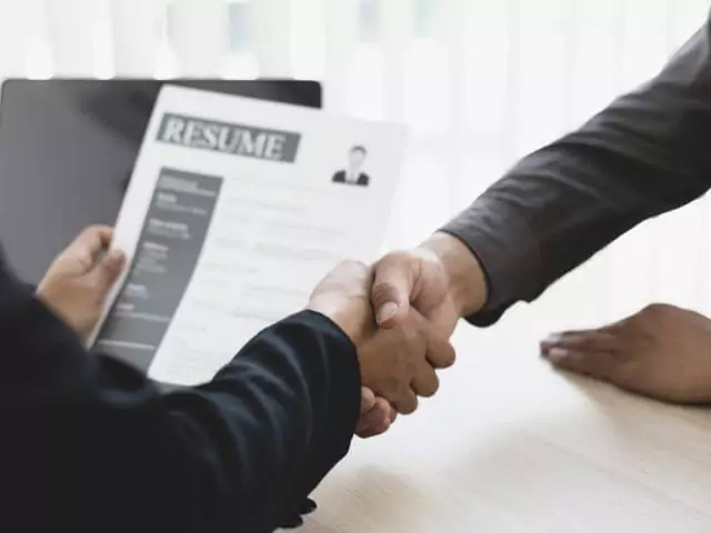 man holding resume shaking hands with candidate