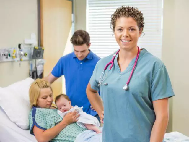midwife standing infront of mother with new baby