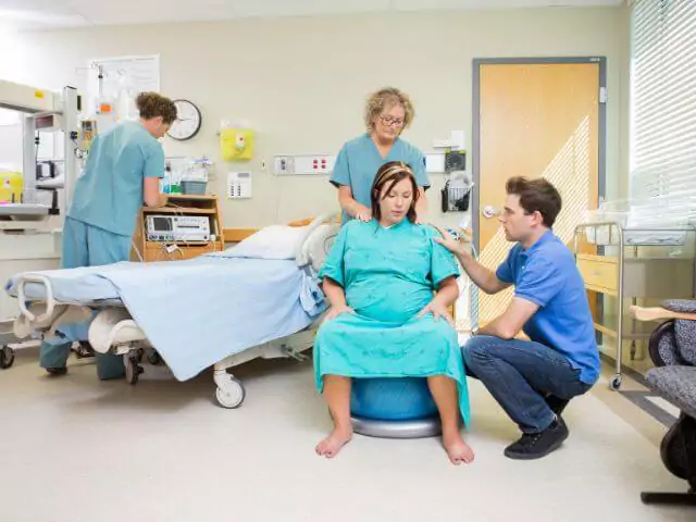 pregnant woman sat on balance ball with midwife