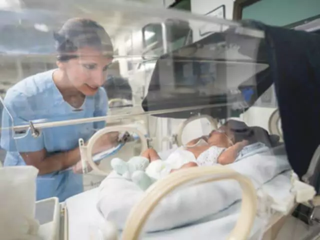 baby in intensive care being taken care of by nurse