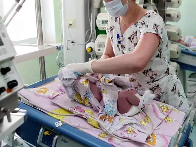 neonatal nurse dressing newborn baby