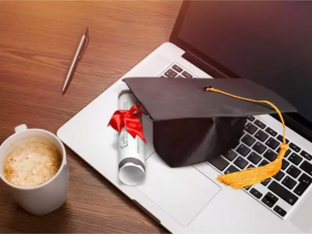 certificate and graduation hat sitting on laptop