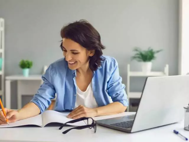 woman learning online and writing on notepad