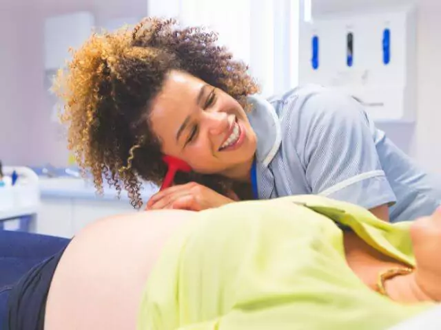 midwife listening to pregnant womans stomach