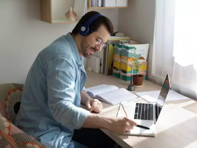 man sitting at desk studying on laptop
