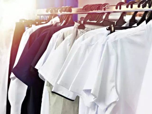 multiple nurses uniforms hanging on clothes rail