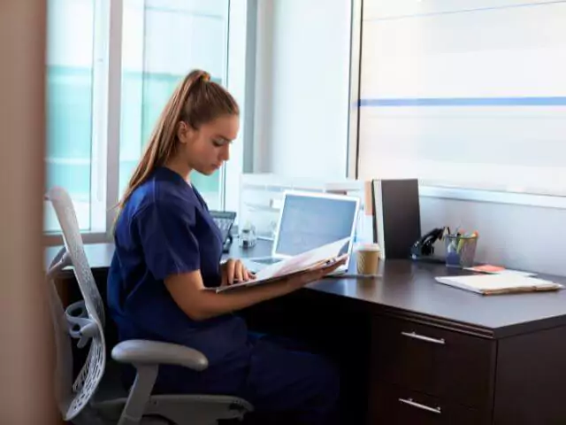 nurse sitting at desk reading paperwork