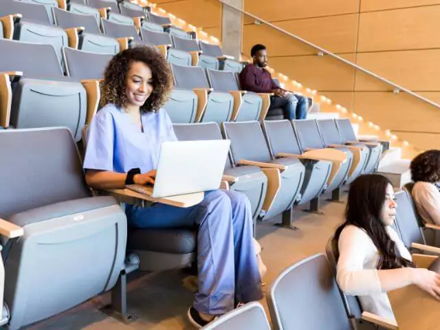 nurse making notes on laptop in lecture hall