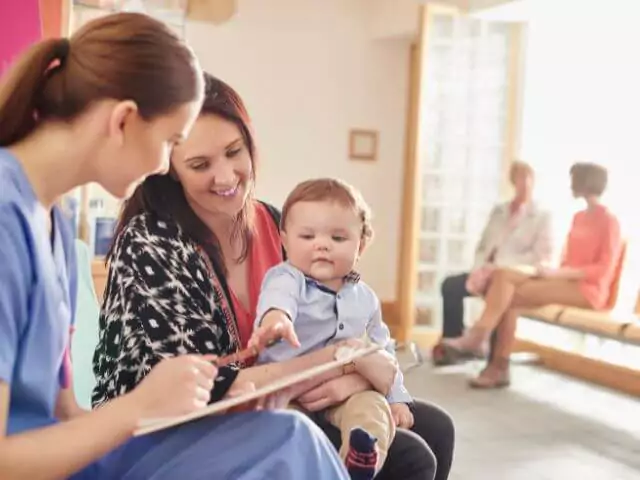 nurse talking to mum and baby and writing on notepad