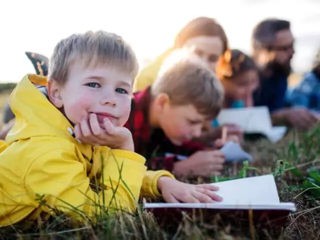 young children laying on grass reading books