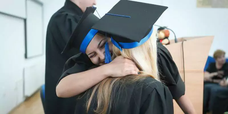 university students hugging after graduating