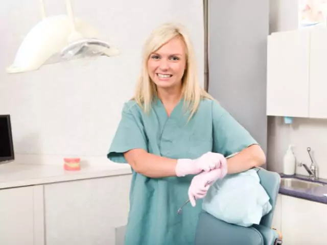 dental nurse smiling leaning on dental chair