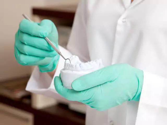 dental nurse using tool on impression of teeth