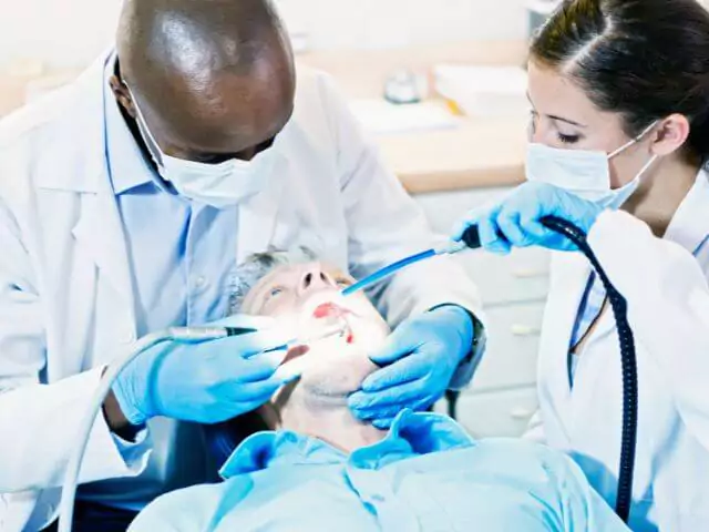 dental nurse using suction machine on patient