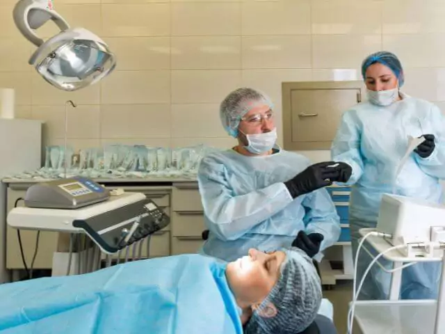 sedated patient being treated by dentist and dental nurse