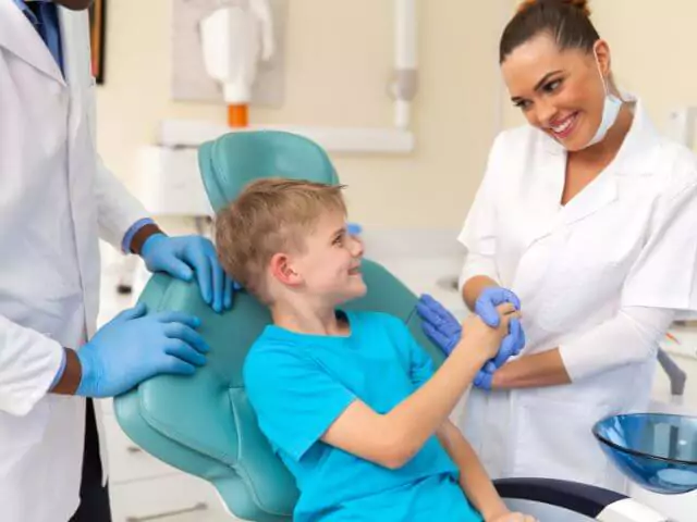 dental nurse shaking hand with boy sitting in dental chair