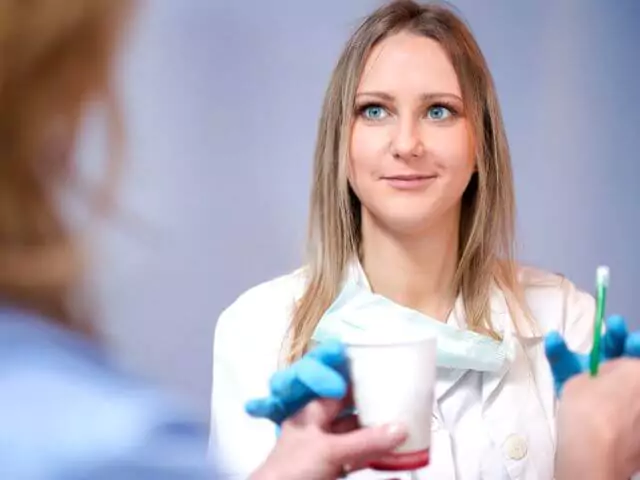 dental nurse taking cup from patient