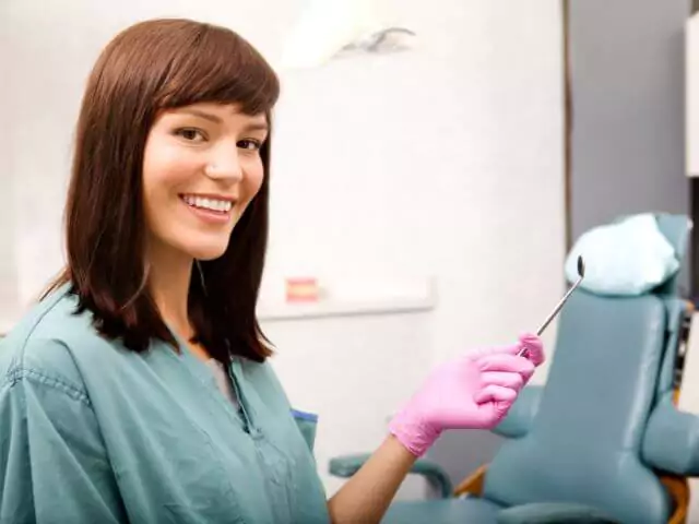 dental nurse holding mirror in surgery