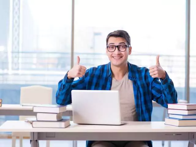 man holding up thumbs studying on laptop
