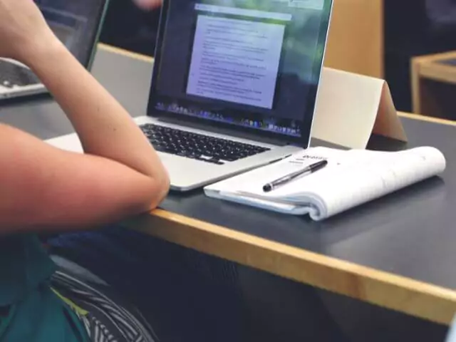 woman studying at desk with laptop and notepad