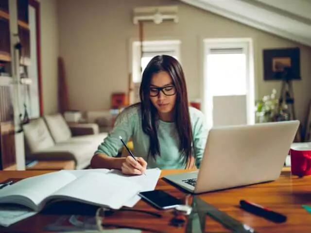 woman studying online course sat at desk with laptop