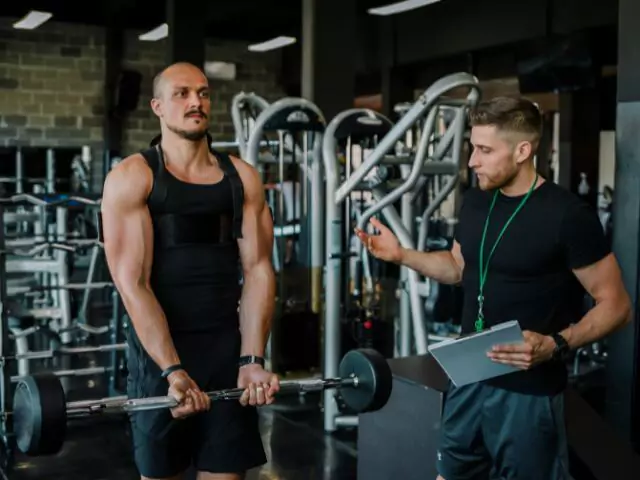 personal trainer teaching weight lifting technique