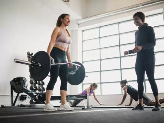 client deadlifting weights whilst personal trainer watches