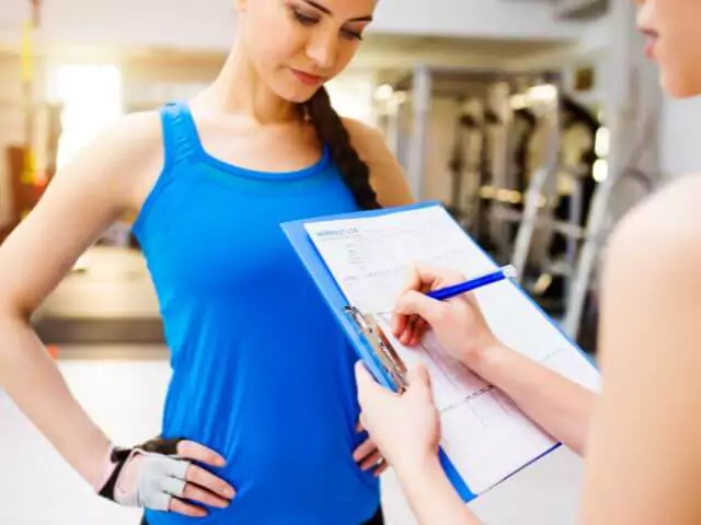 personal trainer with client writing notes on clipboard