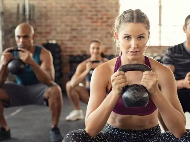 fitness class doing squats holding kettle bells