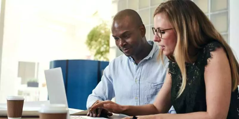 man and woman sat at desk studying on laptop