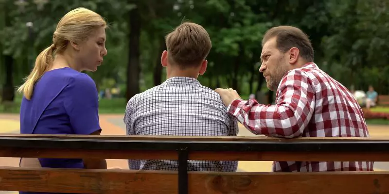 mum and dad talking to son sitting on bench