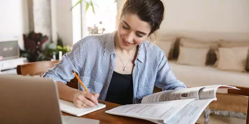 woman studying online course writing in notepad