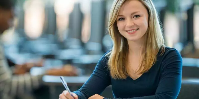 young student holding a pen looking at the camera