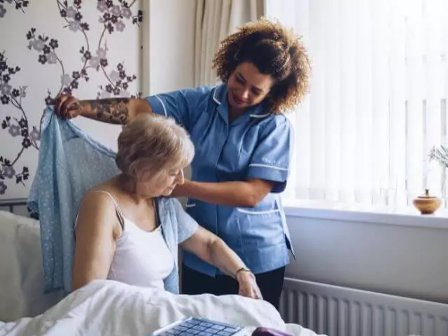 Carer Helping Old Woman Get Dressed