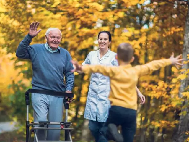 Child Running To Granddad And Carer