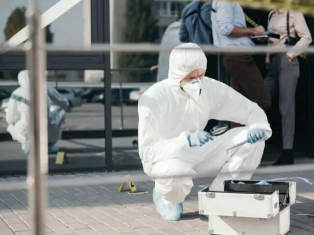 man in forensic suit examining crime scene
