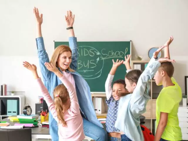 kids and teaching assistant holding hands in air