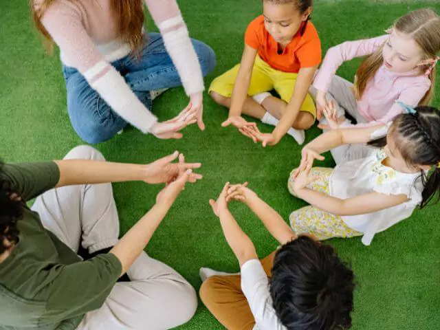 kids sitting in a circle with teaching assistant