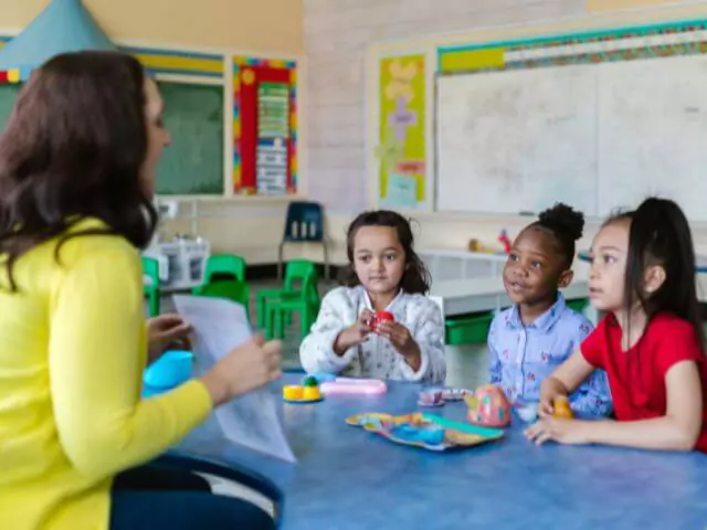 teaching assistant showing kids writing on paper