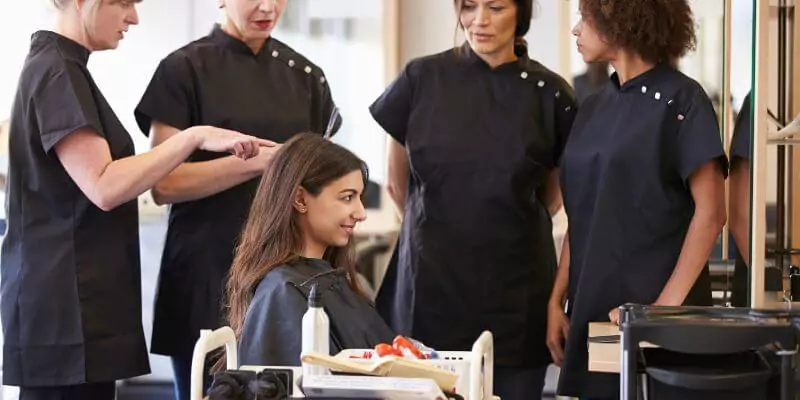 four hairdressers talking and cutting hair