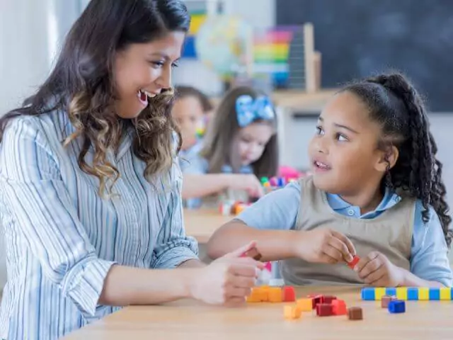 maths teacher using blocks to teach child maths